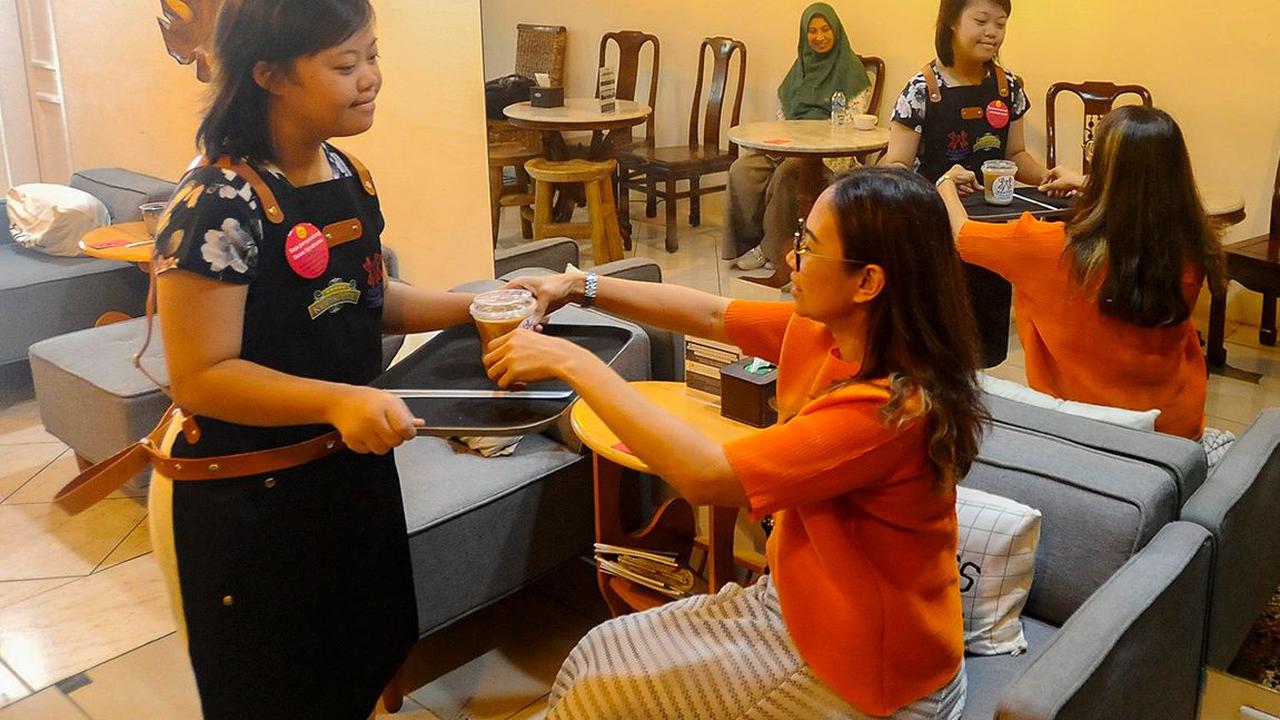 Penyandang down syndrome menyajikan kopi untuk pengunjung di Kopi Kamu, Kebayoran Baru, Jakarta Selatan, pada Selasa (5/12/2023). Coffee shop yang berada di bawah naungan Persatuan Orang Tua Anak Dengan Down Syndrome (POTADS) ini memberikan kesempatan bag