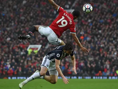 Pemain Manchester United, Marcus Rashford (atas) melakukan duel dengan pemain West Bromwich, Jay Rodriguez pada lanjutan Premier League di Old Trafford, Manchester,(15/4/2018). Manchester United kalah 0-1. (AFP/Paul Ellis)