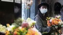 Penjual bunga Zhao Yuanyuan mengenakan masker mengatur bunga menjelang Hari Valentine di tokonya di Shanghai (12/2/2020). Pasangan-pasangan yang merayakan Hari Valentine di seluruh China dibayangi wabah virus corona COVID-19. (AFP Photo/Noel Celis)