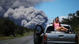 Seorang wanita berswafoto di atas mobil dengan latar belakang kepulan abu vulkanik dari gunung berapi Kilauea di Big Island Hawaii (15/5). Penduduk mendapat peringatan mengenai abu yang dapat menganggu pernapasan. (Mario Tama/Getty Images/AFP)