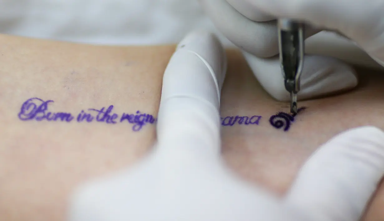 Seorang wanita mentato bagian lengannya untuk menghormati Raja Bhumibol Adulyadej di Bangkok, Thailand, Selasa (18/10). Tato tersebut berbunyi "Lahir di masa pemerintahan Raja Rama IX". (REUTERS / Athit Perawongmetha)