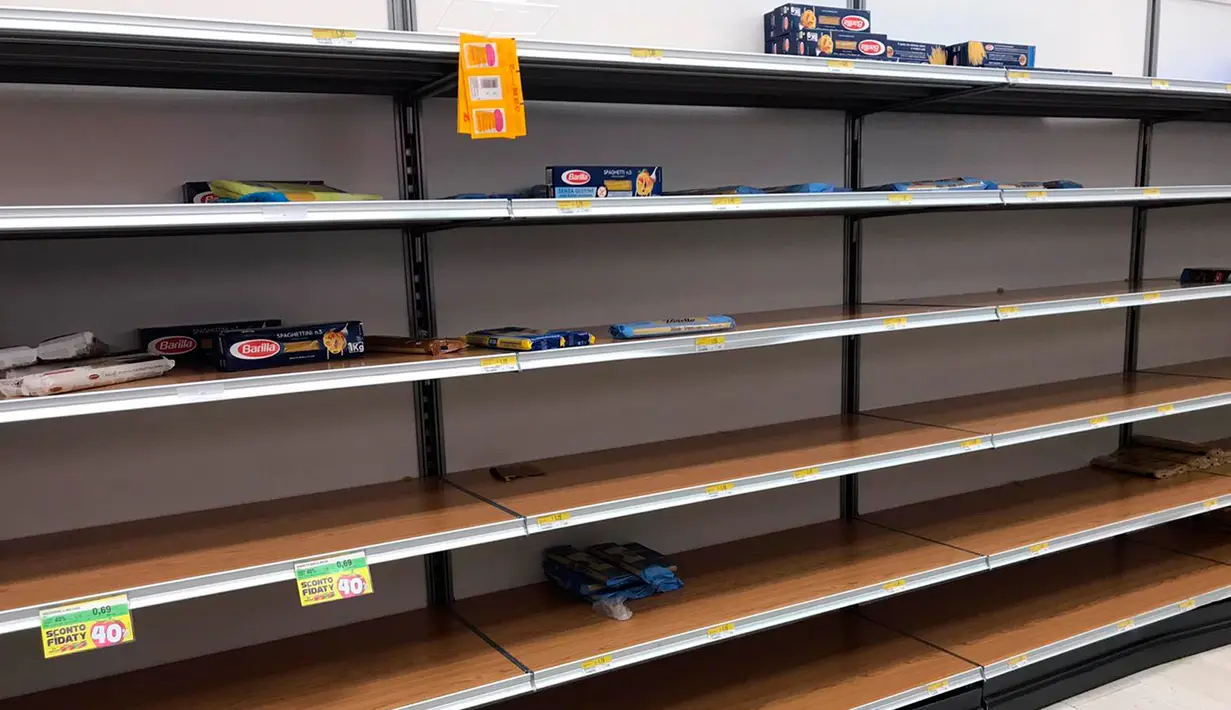 Rak-rak kosong terlihat di sebuah supermarket di Rozzano, dekat Milan, Minggu (23/2/2020). Orang-orang memborong perlengkapan dan bahan-bahan kebutuhan pokok karena tak mau keluar rumah menyusul dua warga Italia yang dipastikan meninggal karena Virus Corona COVID-19 . (AP/Antonio Calanni)