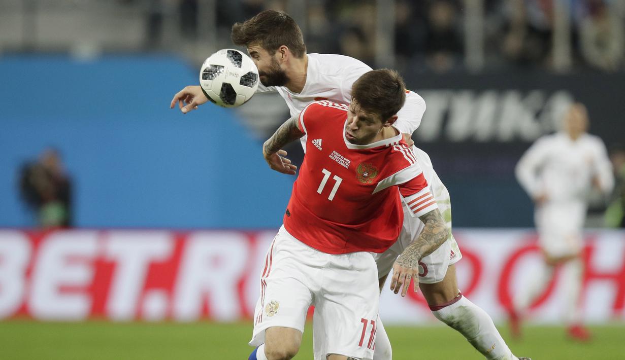 Duel pemain Rusia, Fedor Smolov (kanan) dan pemain Spanyol, Gerard Pique pada laga persahabatan di St.Petersburg, Russia, (14/11/2017). Spanyol bermain imbang 3-3 lawan Rusia. (AP/Dmitri Lovetsky)
