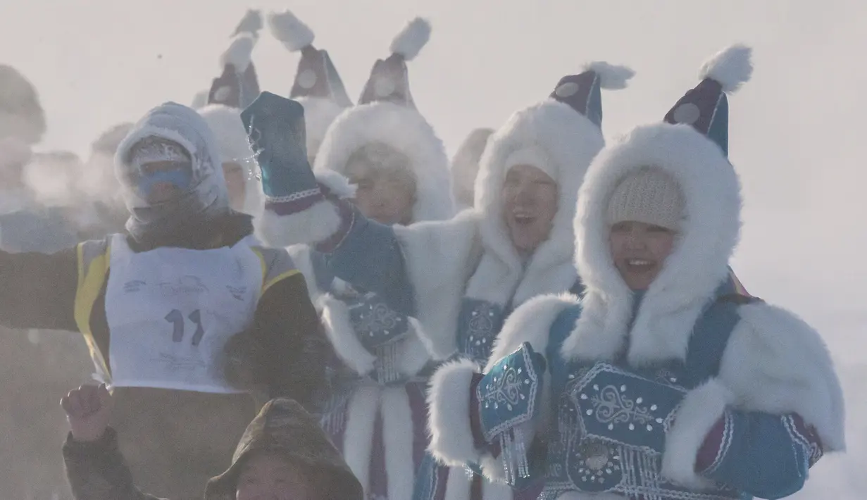 Perempuan yang mengenakan kostum nasional Yakutian mendukung pelari yang ikut serta dalam maraton terdingin di Dunia Internasional pada suhu minus 53 derajat (-63,4 Fahrenheit) di dekat Oymyakon, republik Sakha, juga dikenal sebagai Yakutia, Rusia, pada 22 Januari 2022. (AP Photo/Ivan Nikiforov)