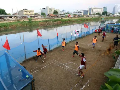 Warga bermain dalam kompetisi sepak bola di pinggir Kali Banjir Kanal Barat, Jakarta, Sabtu (5/11). Minimnya sarana bermain sepak bola mengakibatkan warga terpaksa memanfaatkan lahan di pinggir kali tersebut untuk bermain. (Liputan6.com/Johan Tallo)
