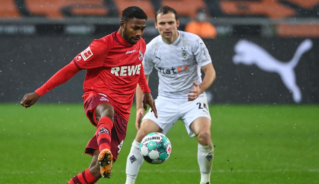 Striker FC Koln, Emmanuel Dennis (kiri) menguasai bola dibayangi bek Borussia Moenchengladbach, Tony Jantschke  dalam laga lanjutan Liga Jerman 2020/21 pekan ke-20 di Borussia Park, Sabtu (6/2/2021). FC Koln menang 2-1 atas Borussia Moenchengladbach. (AFP/Ina Fassbender/Pool)