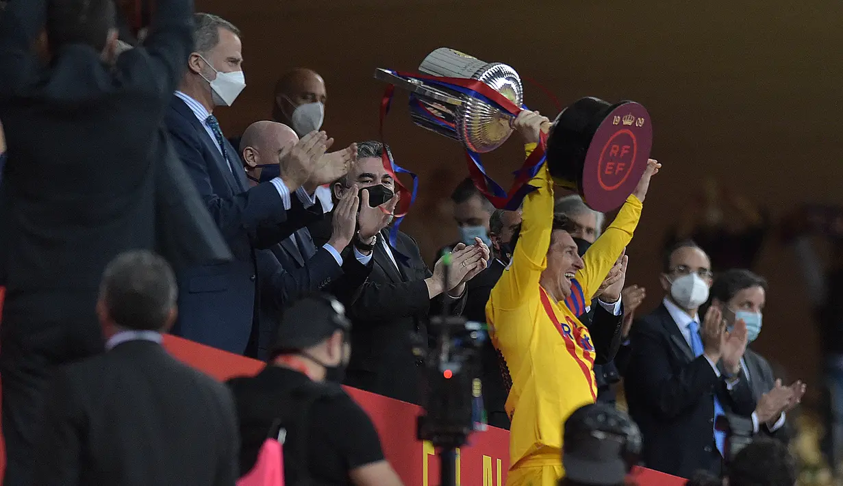 Penyerang Barcelona, Lionel Messi mengangkat trofi usai pertandingan melawan Athletic Bilbao pada final Copa del Rey Spanyol 2021 di stadion La Cartuja di Seville, Spanyol, Minggu (18/4/2021). Messi mencetak dua gol di pertandingan final ini dan mengantar Barcelona menang 4-0. (CRISTINA QUICLER/AFP)