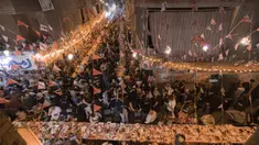 Umat muslim berkumpul di meja sepanjang jalan untuk berbuka puasa bersama dalam jamuan buka puasa massal pada hari ke-15 bulan suci Ramadhan di pinggiran Matariya, timur laut Kairo, Mesir, 16 April 2022. (Khaled DESOUKI/AFP)