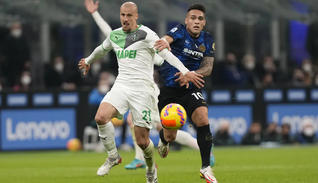 Penyerang Inter Milan, Lautaro Martinez berebut bola dengan pemain Sassuolo, Vlad Chiriches selama pertandingan lanjutan Liga Serie A Italia di Stadion San Siro, di Milan, Italia, Senin (21/2/2022). Inter Milan kalah atas Sassuolo 0-2. (AP Photo/Antonio Calanni)