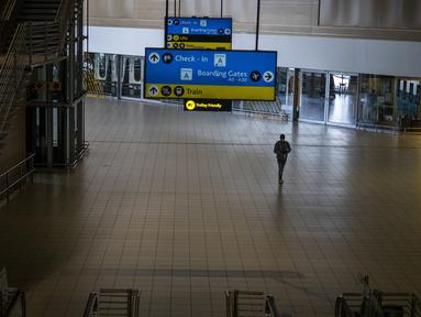 Seorang pria berjalan melalui bagian sepi bandara OR Tambo Johannesburg, Afrika Selatan (29/11/2021). WHO mendesak negara-negara di seluruh dunia untuk tidak memberlakukan larangan penerbangan di negara-negara Afrika selatan karena kekhawatiran atas varian omicron baru. (AP/Jerome Delay)