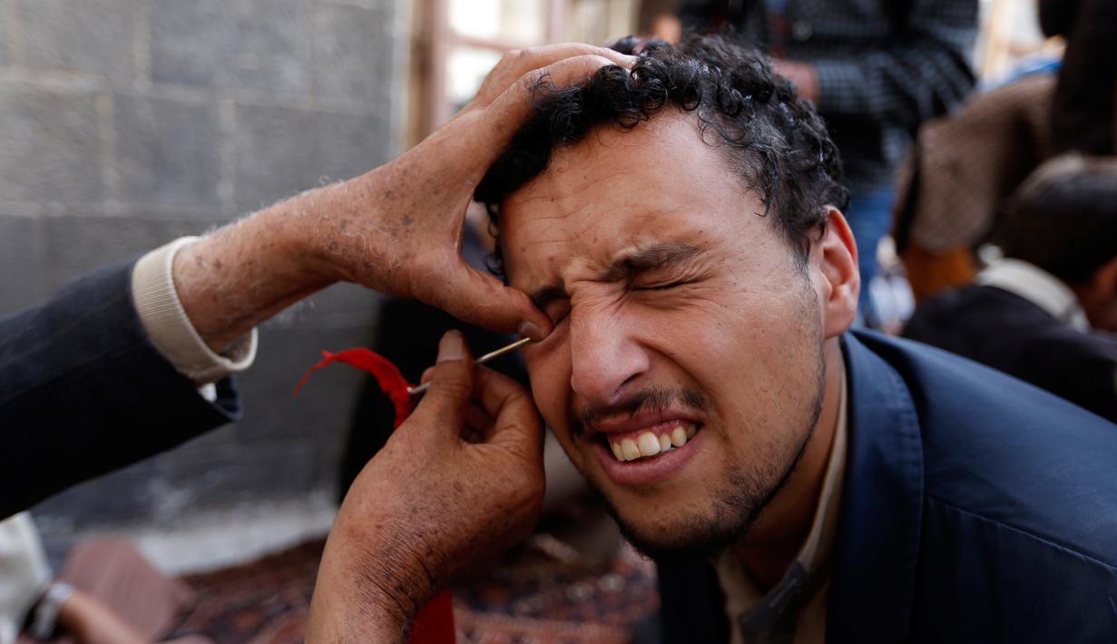 Ekspresi seorang pria saat kelopak matanya dirias dengan kohl atau celak di  Masjid Agun di kota tua ibukota Sanaa, Yama, (19/5). Pemakaian kohl atau celak ini sudah menjadi tradisi muslim Yaman pada setiap bulan Ramadan. (AFP Photo/Mohammed Huvais)
