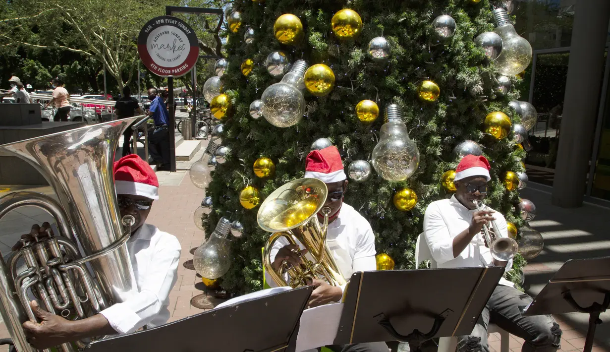Sebuah band kuningan kecil memainkan lagu-lagu Natal untuk pembeli di sebuah mal di Johannesburg, Jumat (24/12/2021). (AP Photo/Denis Farrell)