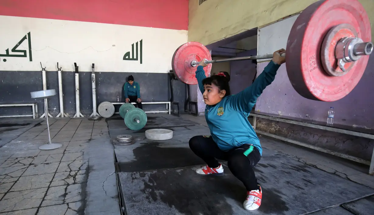 Atlet angkat besi wanita Roqaya Ahmed mengangkat beban saat berlatih di sebuah klub di Kota Sadr, sebelah timur Baghdad, Irak (18/1). (AFP Photo/Ahmad Al-Rubaye)