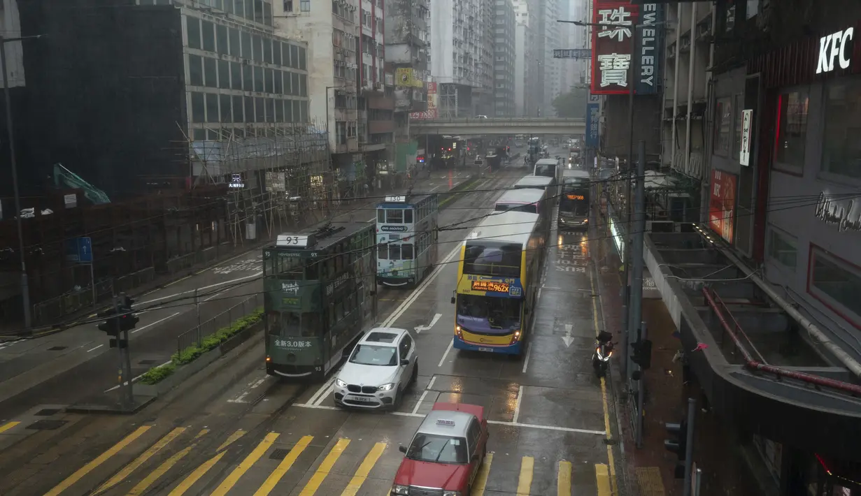 Kendaraan melewati persimpangan di daerah Causeway Bay saat badai tropis Ma-on melewati Hong Kong, Kamis (25/8/2022). Badai Tropis Ma-on semakin kuat saat menuju Hong Kong dan bagian tenggara lainnya China pada hari Rabu setelah menggusur ribuan orang di Filipina. (AP Photo/Anthony Kwan)