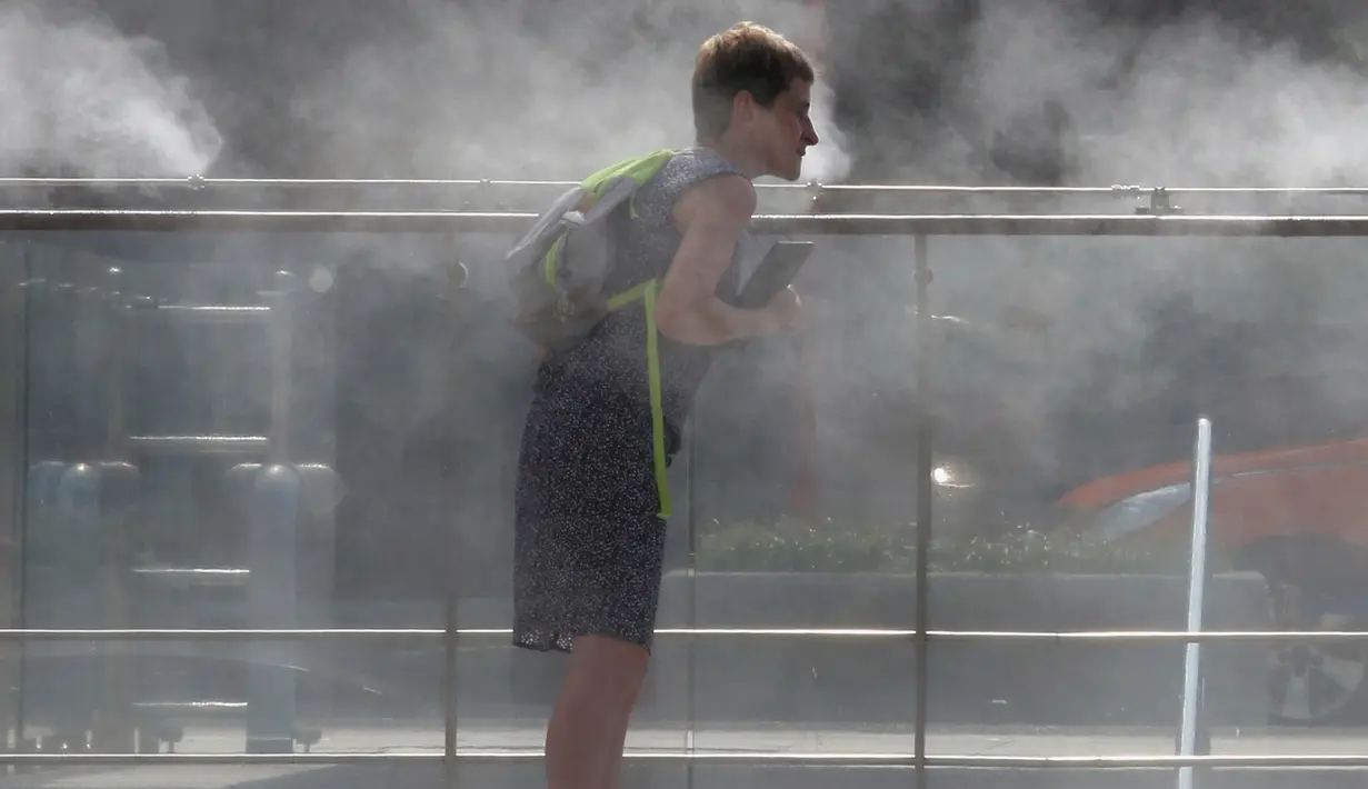Seorang wanita mendinginkan wajahnya di mesin kabut di Gwanghwamun Square di Seoul, Korea Selatan pada 25 Juli 2017. Peringatan gelombang panas dikeluarkan karena suhu melonjak di atas 34 derajat Celsius (93 derajat Fahrenheit). (AP Photo/Ahn Young-joon)