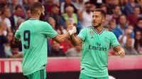 Gelandang Real Madrid, Eden Hazard berselebrasi dengan rekannya Karim Benzema setelah mencetak gol ke gawang Red Bull Salzburg pada laga persahabatan di Red Bull Arena, Austria (8/8/2019). Winger asal Belgia itu mencetak gol perdananya untuk klub barunya Real Madrid. (AFP Photo/Krugfoto)