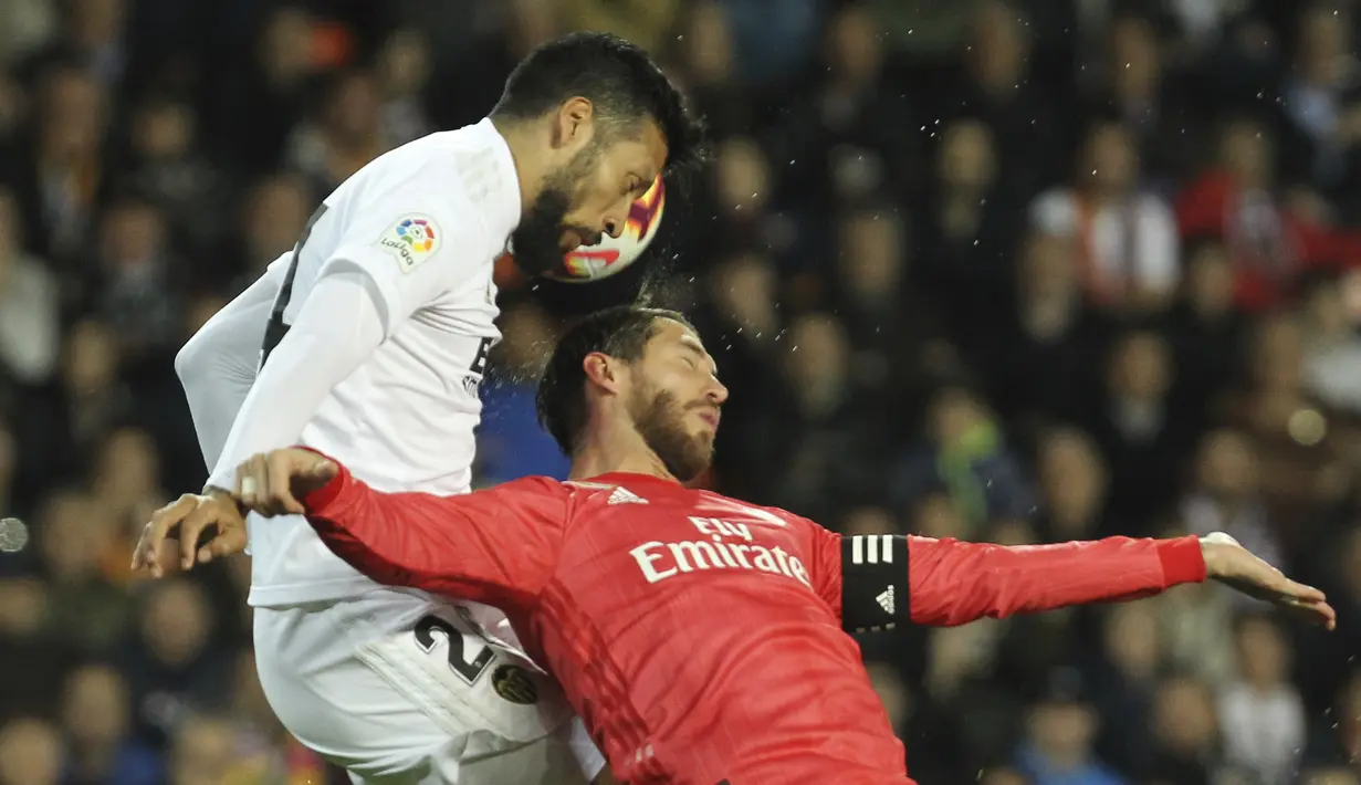 Bek Real Madrid, Sergio Ramos, duel udara dengan pemain Valencia, Ezequiel Garay, pada laga La Liga 2019 di Stadion Mestalla, Rabu (3/4). Valencia menang 2-1 atas Real Madrid. (AP/Alberto Saiz)
