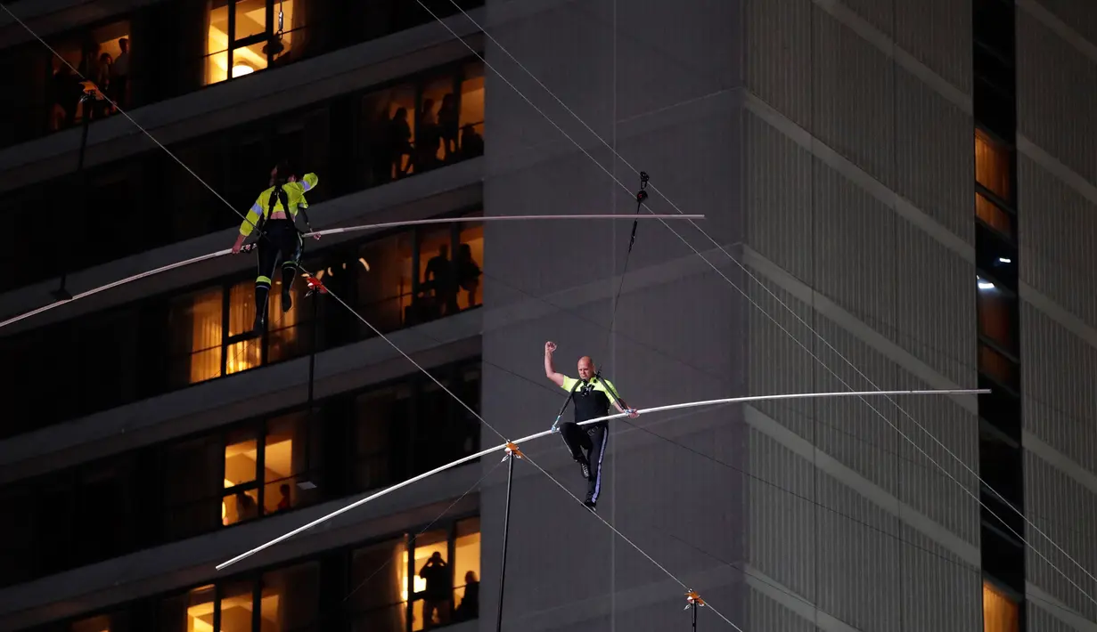 Aerialists Nik Wallenda (kanan) dan saudara perempuannya Lijana Wallenda melintasi seutas kawat di ketinggian 396 meter, Times Square, New York, AS, Minggu (23/6/2019). Aksi berbahaya ini bertajuk Highwire Live In Times Square. (AP Photo/Jason Szenes)