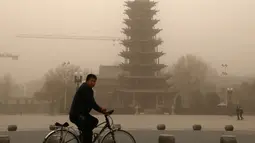 Warga mengayuh sepedanya saat badai pasir di Zhangye, di provinsi Gansu barat laut China (25/11). Menurut pemerintah setempat, sebuah kota di barat laut China ini dilanda badai pasir yang memicu kebakaran di pedesaan.  (AFP Photo/China Out)