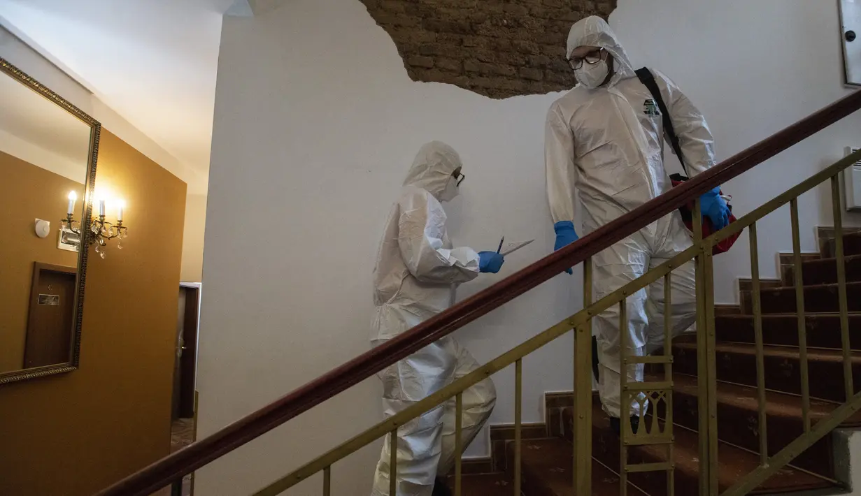 Petugas kesehatan dengan APD menaiki tangga untuk mengunjungi tunawisma pasien virus corona di sebuah hotel di Praha, Senin (8/3/2021). Hotel yang dulu menjadi tujuan wisatawan internasional itu kini membuka pintunya bagi para tunawisma yang terpapar Covid-19 atau perlu karantina. (MICHAL CIZEK/AFP)