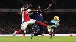 Pemain Arsenal, Bukayo Saka (kiri) berebut bola dengan pemain Arsenal, Tyrell Malacia pada laga lanjutan Liga Inggris 2024/2025 di Emirates Stadium, London, Inggris, Kamis (05/12/2024) WIB. (AP Photo/Kirsty Wigglesworth)