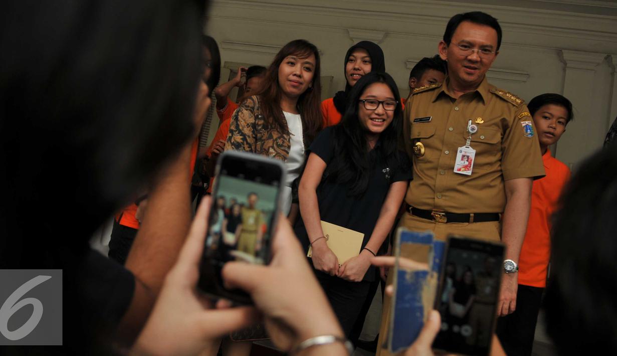 Murid Jakarta Intercultural School (JIS) foto bersama dengan Gubernur Basuki T Purnama usai kunjungan ke Balaikota, Jakarta, Senin (21/3). Kunjungan perdana JIS ini bertujuan untuk menyampaikan komitmen sekolah. (Liputan6.com/Gempur M Surya)