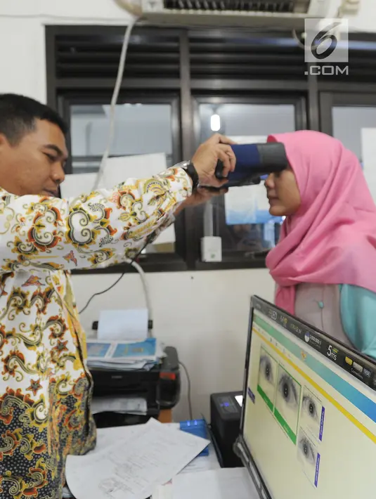 Petugas memindai retina seorang warga saat pembuatan E-KTP di Kantor kelurahan Cinere, Depok, Kamis (27/12). Hari ini Disdukcapil daerah melaksanakan pelayanan jemput bola perekaman E-KTP serentak khusus pemula secara nasional. (Merdeka.com/Arie Basuki)