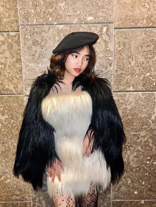 Fuji mengenakan dress outer bulu-bulu dan topi warna hitam senada, yang memberi kesan elegan dan glamor. Penampilannya dipermanis dengan kalung putih yang dipakainya. (instagram/fuji_an)