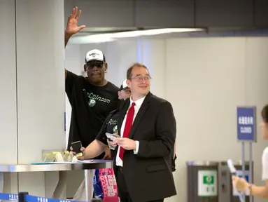 Mantan pemain NBA Dennis Rodman menyapa awak media saat bersiap pergi melalui imigrasi di Bandara Internasional di Beijing, (13/6). Rodman tiba di Korut pada kunjungan pertamanya sejak Presiden Donald Trump mulai menjabat. (AP Photo/Mark Schiefelbein)