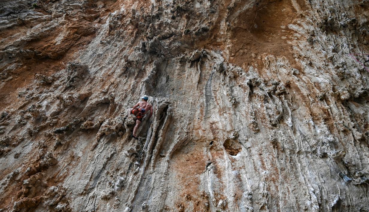 Peserta berusaha memanjat tebing dalam Festival Mendaki tahunan 2019 di pulau Kalymnos, Yunani (4/10/2019). Pemandangan menakjubkan dan cuaca bagus menjadikan pulau ini sebagai tujuan utama bagi pemanjat dari semua tingkatan dengan lebih dari 2500 rute pendakian. (AFP Photo/Aris Messinis)
