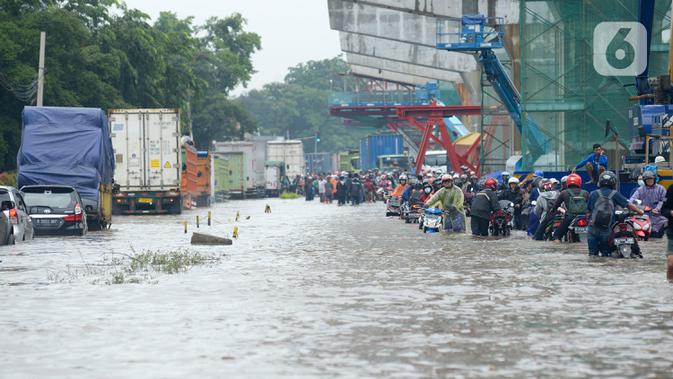Pengendara mendorong motornya melintasi banjir di Jalan Raya Bekasi, Jakarta Timur, Selasa (25/2/2020). Banjir akibat hujan yang melanda Bekasi sejak Selasa (25/2) dini hari memutus beberapa titik jalan raya di wilayah setempat. (merdeka.com/Imam Buhori)