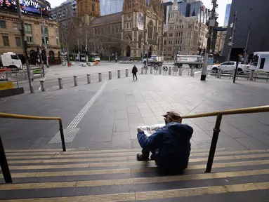Seorang pria membaca koran di tangga Stasiun Flinders Street di Melbourne, Australia, Rabu (11/8/2021). Lima juta orang di kota terbesar kedua di Australia tersebut akan tetap berada di bawah perintah tinggal di rumah, setidaknya selama seminggu lagi. (AAP Image/Daniel Pockett)