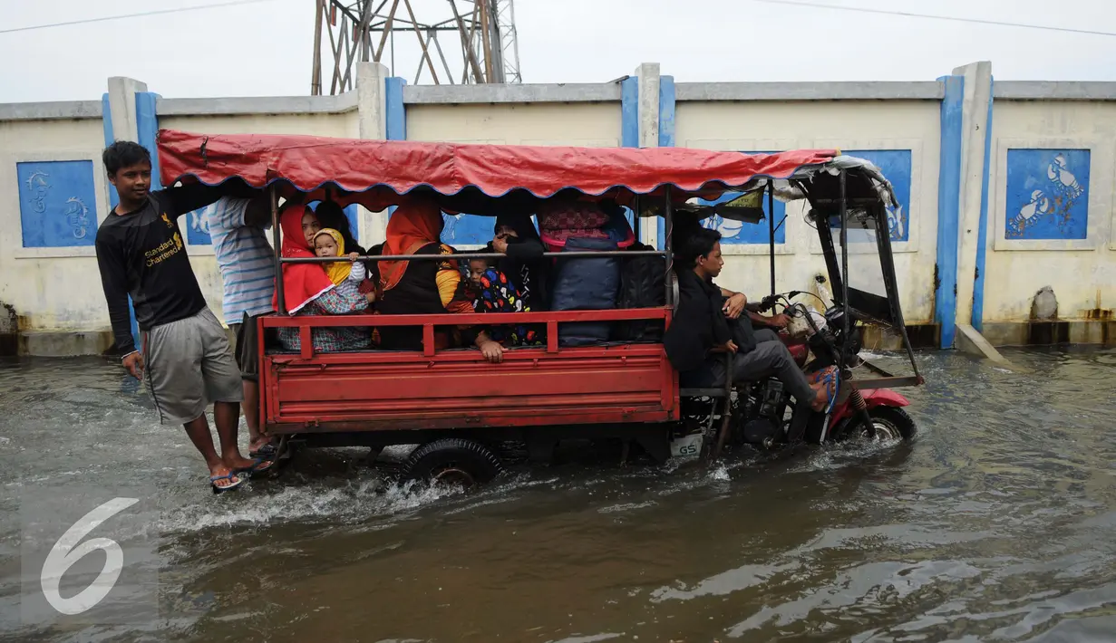 Sejumlah warga menumpang gerobak motor melitasi banjir di Kawasan Muara Angke, Jakarta, Rabu (11/1). Sejak jebolnya tanggul sampai saat ini tidak ada perbaikan yang dilakukan pemerintah pusat dan daerah. (Liputan6.com/Gempur M. Surya)