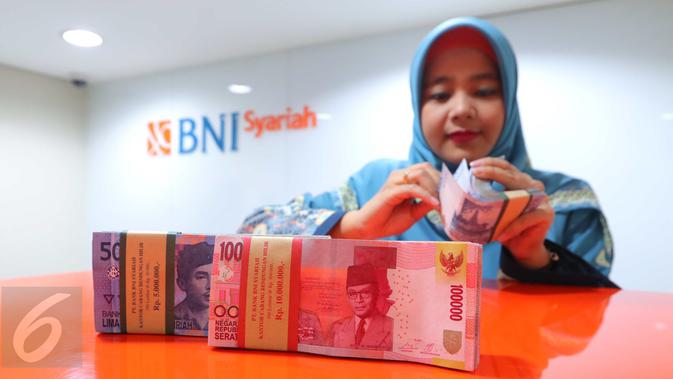 Pekerja menghitung uang di BNI Syariah Jakarta, Senin (10/10). Sejalan dengan perkembangan share tersebut, kenaikan aset perbankan syariah (BUS dan UUS) sebesar 18,49% (YOY), dari Rp 272,6 triliun menjadi Rp 305,5 triliun. (Liputan6.com/Angga Yuniar)