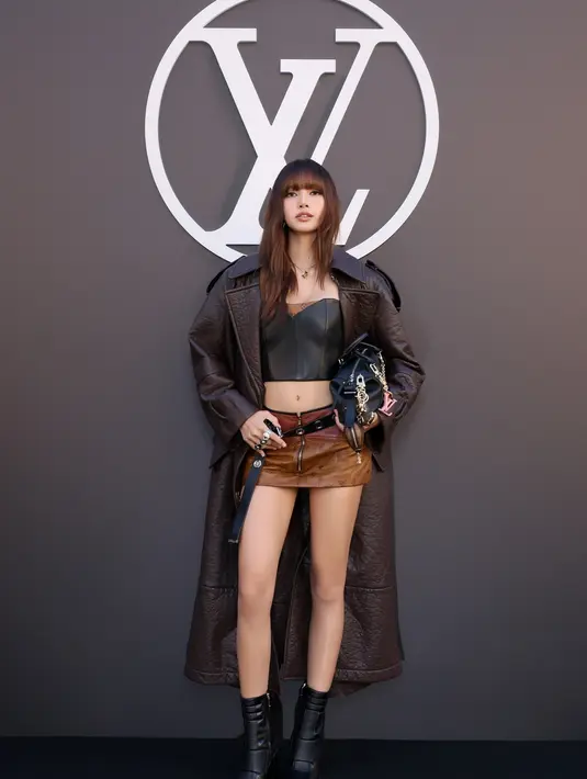 Lisa BLACKPINK tampil ala rockstar dengan korset kulit dan rok mini cokelat. Dipadukan dengan long coat kulit dan sepatu boots hitam [Louis Vuitton]