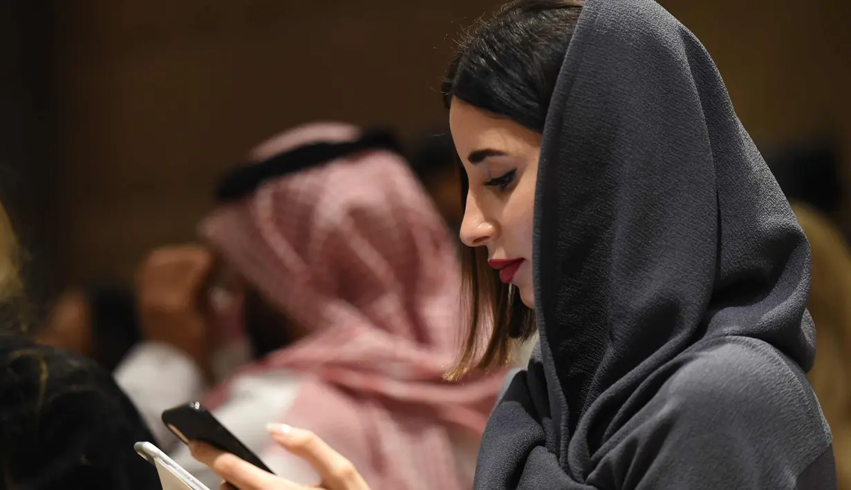 Seorang wanita bermain ponsel saat menghadiri upacara pembukaan Arab Fashion Week di hotel Ritz Carlton di Riyadh (10/4). Arab Fashion Week akan berlangsung hingga 14 April 2018. (AFP Photo/Fayez Nureldine)