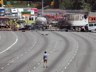 Penyidik memeriksa bangkai truk yang telah hangus usai terjadi tabrakan antara dua truk besar di utara pusat kota Los Angeles (25/4). Kecelakaan ini menewaskan satu orang dan melukai sejumlah orang lainnya. (AP Photo/Reed Saxon)