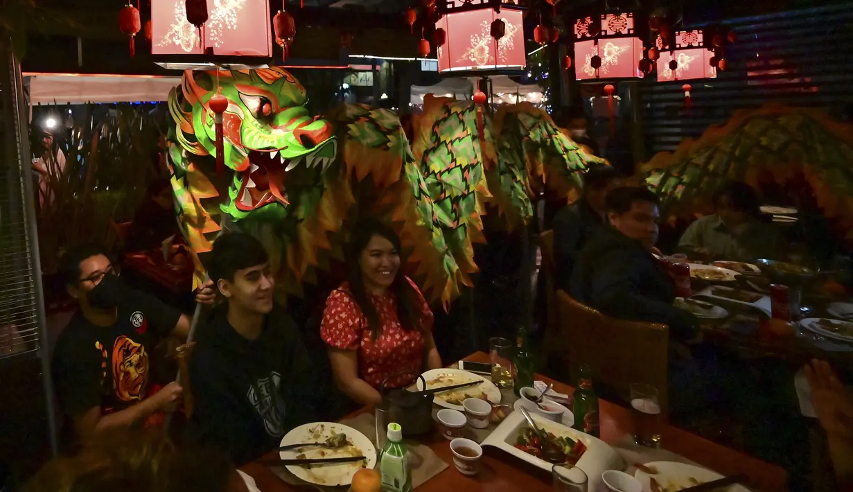 Anggota komunitas Tionghoa di Meksiko menampilkan tarian naga tradisional (liong) di sebuah restoran Tiongkok menyambut Tahun Baru Imlek di Mexico City, pada 31 Januari 2022. Tahun Baru Imlek 2022 menandai dimulainya tahun Shio Macan Air. (PEDRO PARDO / AFP)