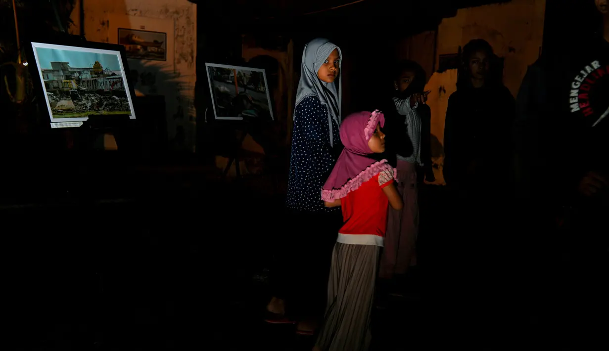 Sejumlah warga menghadiri upacara doa pada malam peringatan 17 tahun tsunami Boxing Day 2004 di monumen Kapal Tsunami Lampulo di Banda Aceh (25/12/2021). (AFP/Chaideer Mahyuddin)