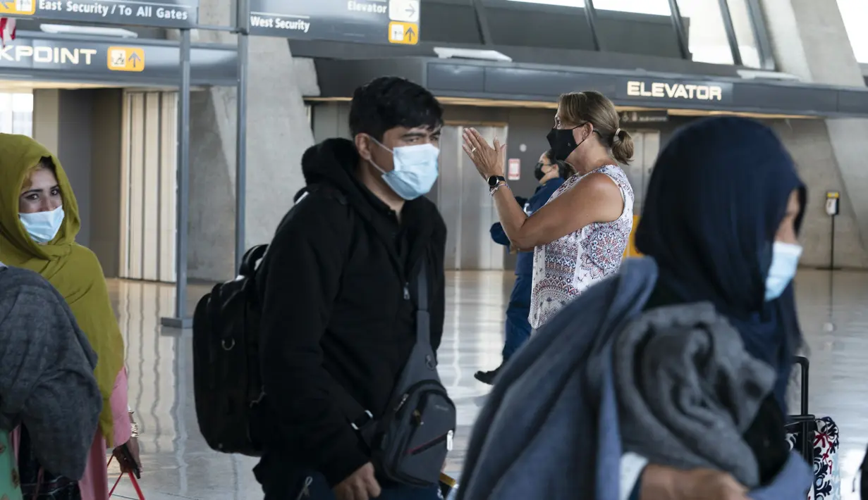 Keluarga dievakuasi dari Kabul, Afghanistan, berjalan melalui terminal sebelum naik bus setelah mereka tiba di Bandara Internasional Washington Dulles, di Chantilly, Va, Rabu (25/8/2021). (AP Photo/Jose Luis Magana)