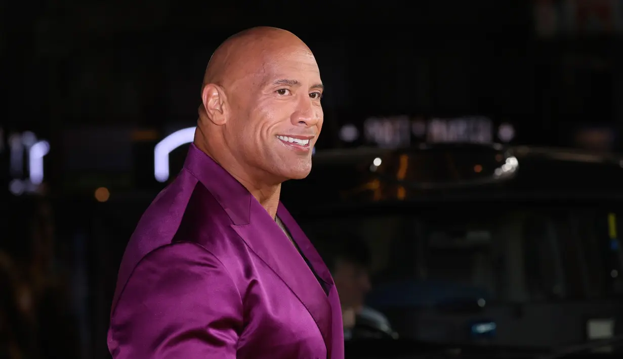 Dwayne Johnson berpose untuk fotografer saat tiba pada pemutaran perdana film 'Black Adam' di London, Inggris, 18 Oktober 2022. Melengkapi penampilannya, Dwayne Johnson memakai kalung perak yang melingkar di leher lencangnya. (Photo by Vianney Le Caer/Invision/AP)