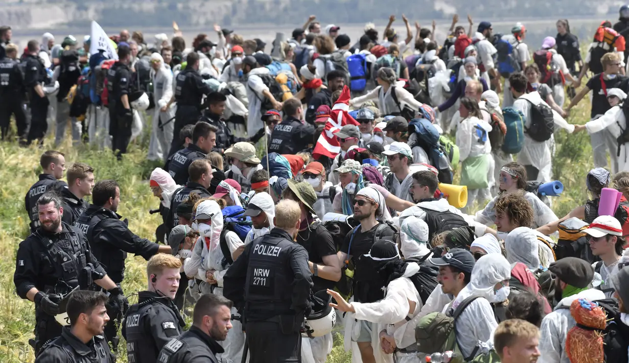 Polisi menjaga unjuk rasa aktivis iklim di tambang batu bara lignit Garzweiler di Garzweiler, Jerman barat, Sabtu (22/6/2019). Para aktivis menuntut tindakan terhadap pemanasan global yang sekarang menjadi salah satu isu terpanas dalam agenda politik Eropa. (INA FASSBENDER/AFP)
