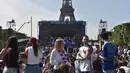 Sejumlah warga berkumpul di sekitar layar raksasa yang terdapat pada acara Champs de Mars yang digelar untuk menyambut Piala Eropa 2016 di Paris fan zone, belakang Menara Eiffel, Prancis, Jumat (10/6/2016). (AFP/Alain Jocard)