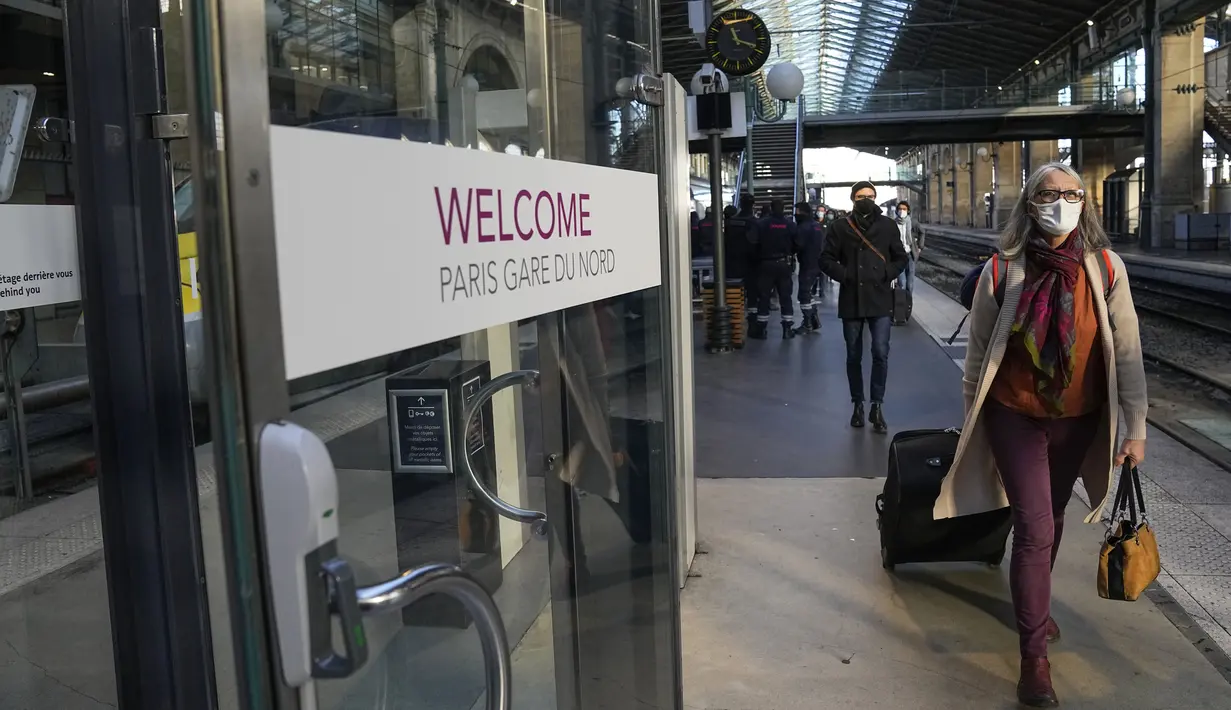 Penumpang yang tiba dari London dengan kereta Eurostar, mengenakan masker untuk melindungi dari COVID-19 keluar dari gerbang kedatangan di stasiun kereta Gare du Nord, Paris, Jumat (14/1/2022). Prancis telah mencabutnya Larangan COVID terhadap turis Inggris mulai (14/1). (AP Photo/Michel Euler)