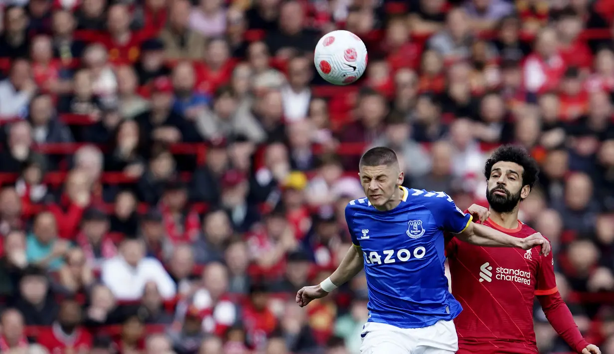 <p>Penyerang Liverpool, Mohamed Salah berebut bola dengan pemain Everton, Vitaliy Mykolenko selama pertandingan pertandingan lanjutan Liga Inggris di stadion Anfield di Liverpool, Inggris, Minggu (24/4/2022). Liverpool menang atas Everton dengan skor 2-0. (AP Photo/Jon Super)</p>