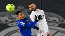 Bek Real Madrid, Nacho Fernandez (kanan) berduel udara dengan striker Getafe, Cucho Hernandez dalam laga lanjutan Liga Spanyol 2020/21 pekan ke-22 di Alfredo di Stefano Stadium, Selasa (9/2/2021). Real Madrid menang 2-0 atas Getafe. (AFP/Gabriel Bouys)