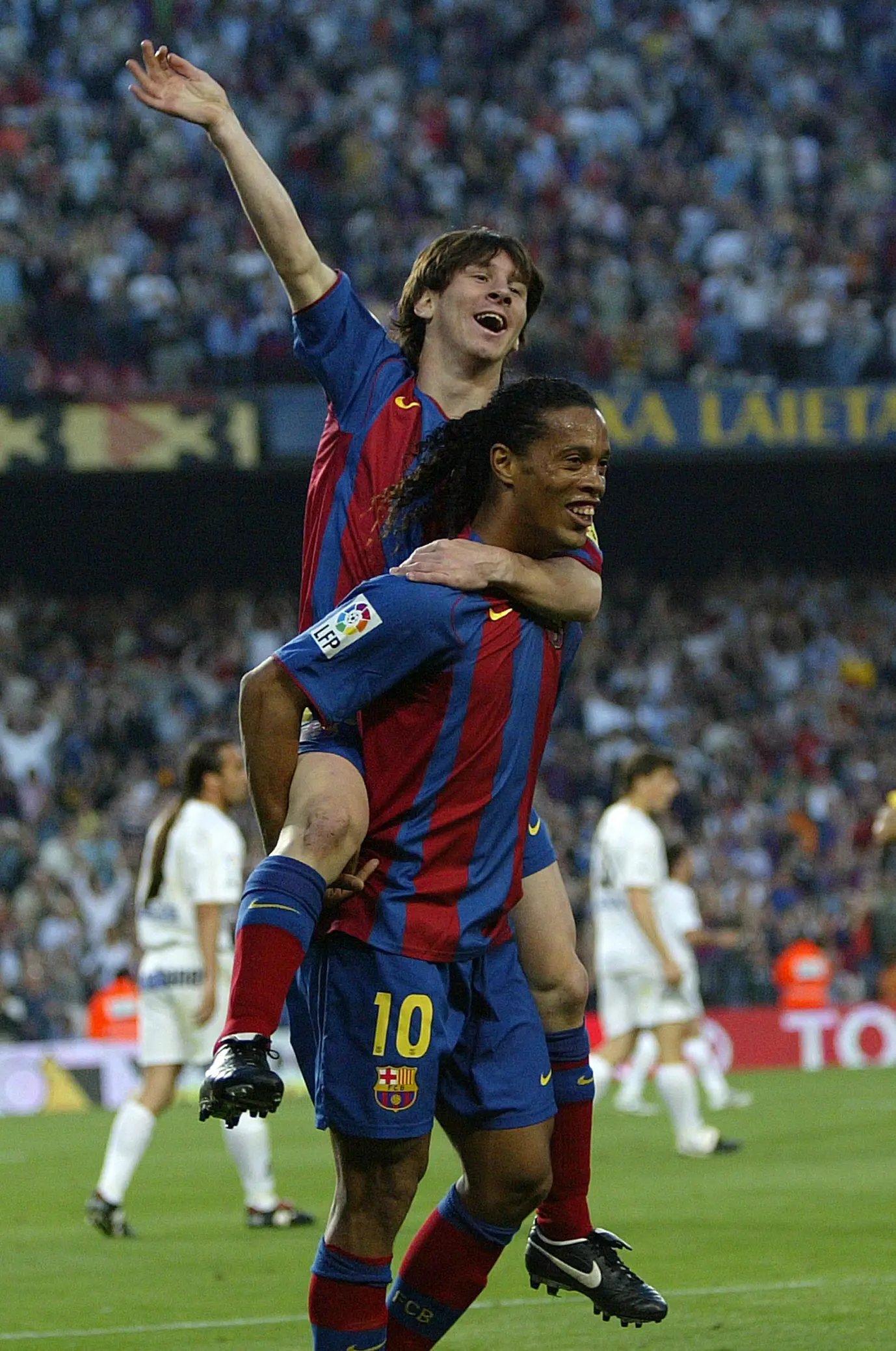 Ronaldinho menggendong Lionel Messi usai memberikan assist untuk gol pertamanya bagi Barcelona. (AFP/Lluis Gene) 