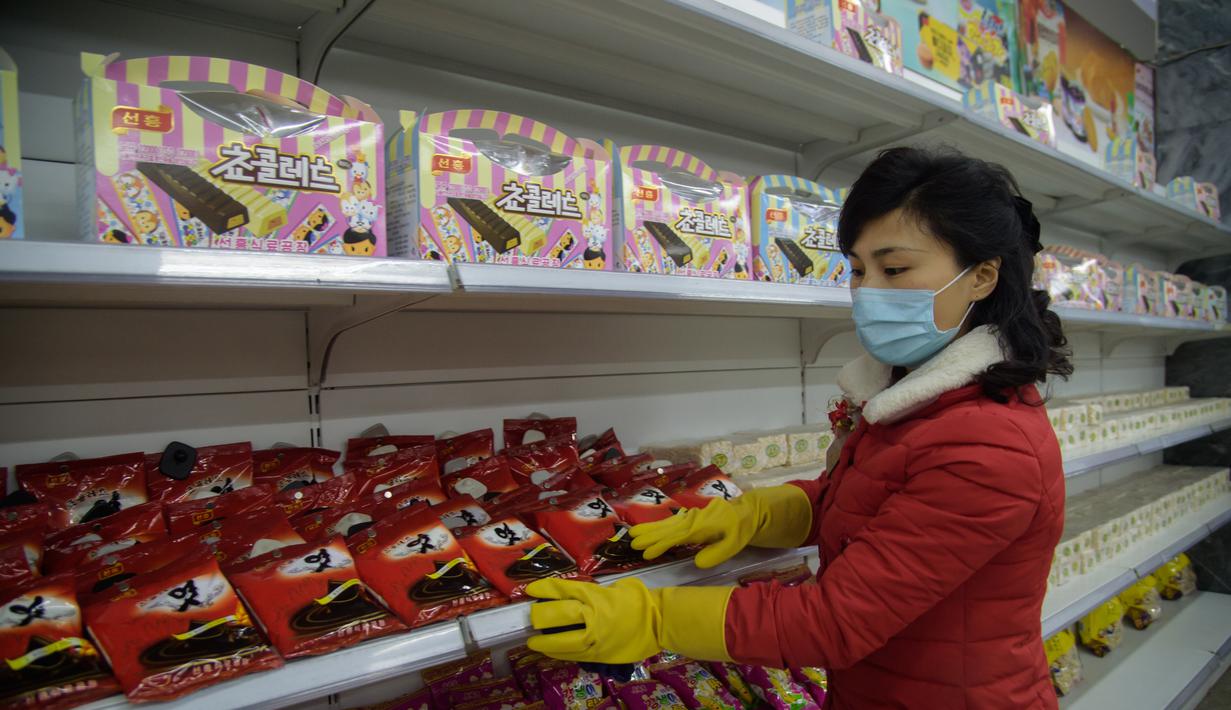 Petugas memakai masker dan sarung tangan menata produk yang dijual di Pyongyang Department Store No. 1 saat penerapan standar protokol kesehatan di Pyongyang, Korea Utara (28/12/2020). (AFP/Kim Won Jin)