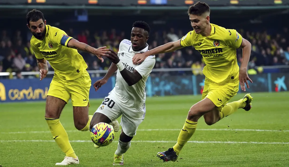 <p>Penyerang Real Madrd, Vinicius Junior berusaha melewati dua pemain Villarreal, Raul Albiol dan Juan Foyth selama pertandingan lanjutan La Liga Spanyol di Estadio De La Ceramica di Villareal, Spanyol, Sabtu (7/1/2023). Kekalahan ini tidak mengubah posisi Real Madrid di peringkat dua klasemen sementara Liga Spanyol 2022-2023 dengan perolehan 38 poin. (AP Photo/Alberto Saiz)</p>