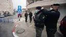 Seorang aparat kepolisian Palestina membantu rekannya mengenakan masker saat bertugas di luar Angel Hotel di Kota Betlehem, Tepi Barat, pada 6 Maret 2020. Keadaan darurat mulai diberlakukan pada Jumat (6/3) di Palestina di tengah kekhawatiran penyebaran coronavirus baru. (Xinhua/Stringer)